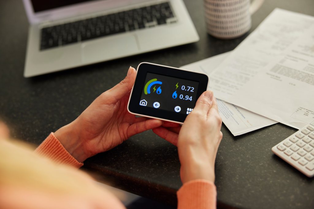 A woman's hands holding a smart meter. The UK government's ECO+ scheme can provide households with fully funded home upgrades