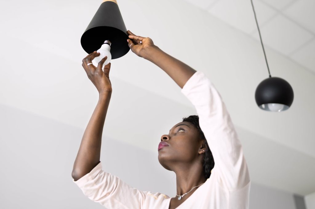 a woman changing a light bulb to LED lighting as these are the most energy efficient lightbulbs 