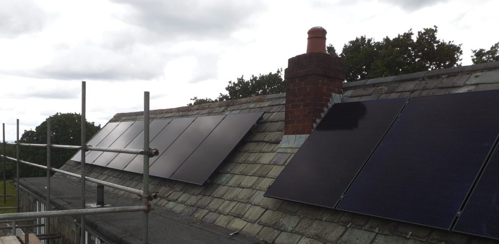 solar panels newly fixed onto a domestic roof. scaffolding is to the left to allow for safe access