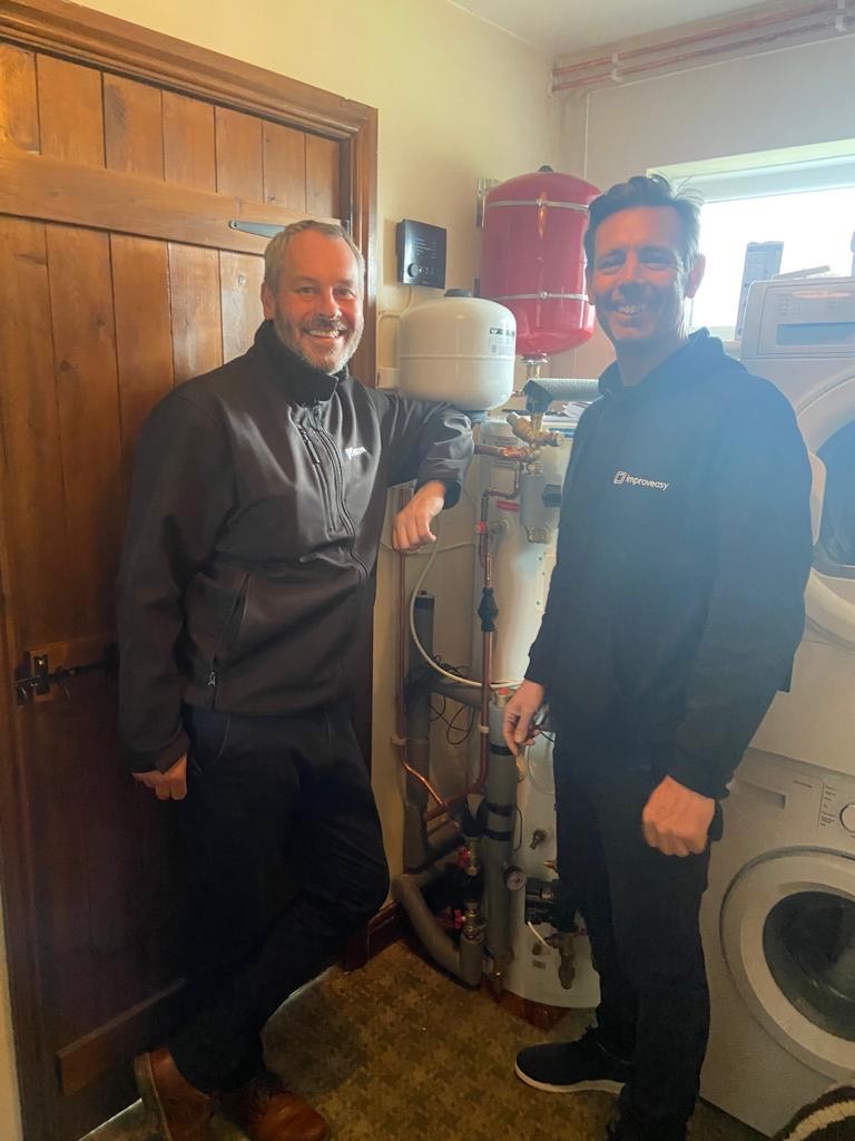 two installers smiling with a newly installed hot water cylinder 