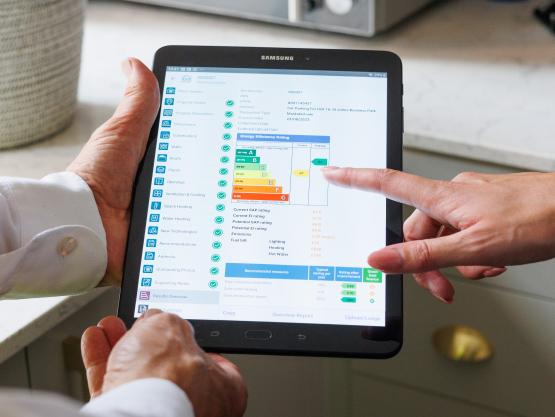 Homeowner reviewing EPC rating and energy efficiency improvements on a tablet with an installer