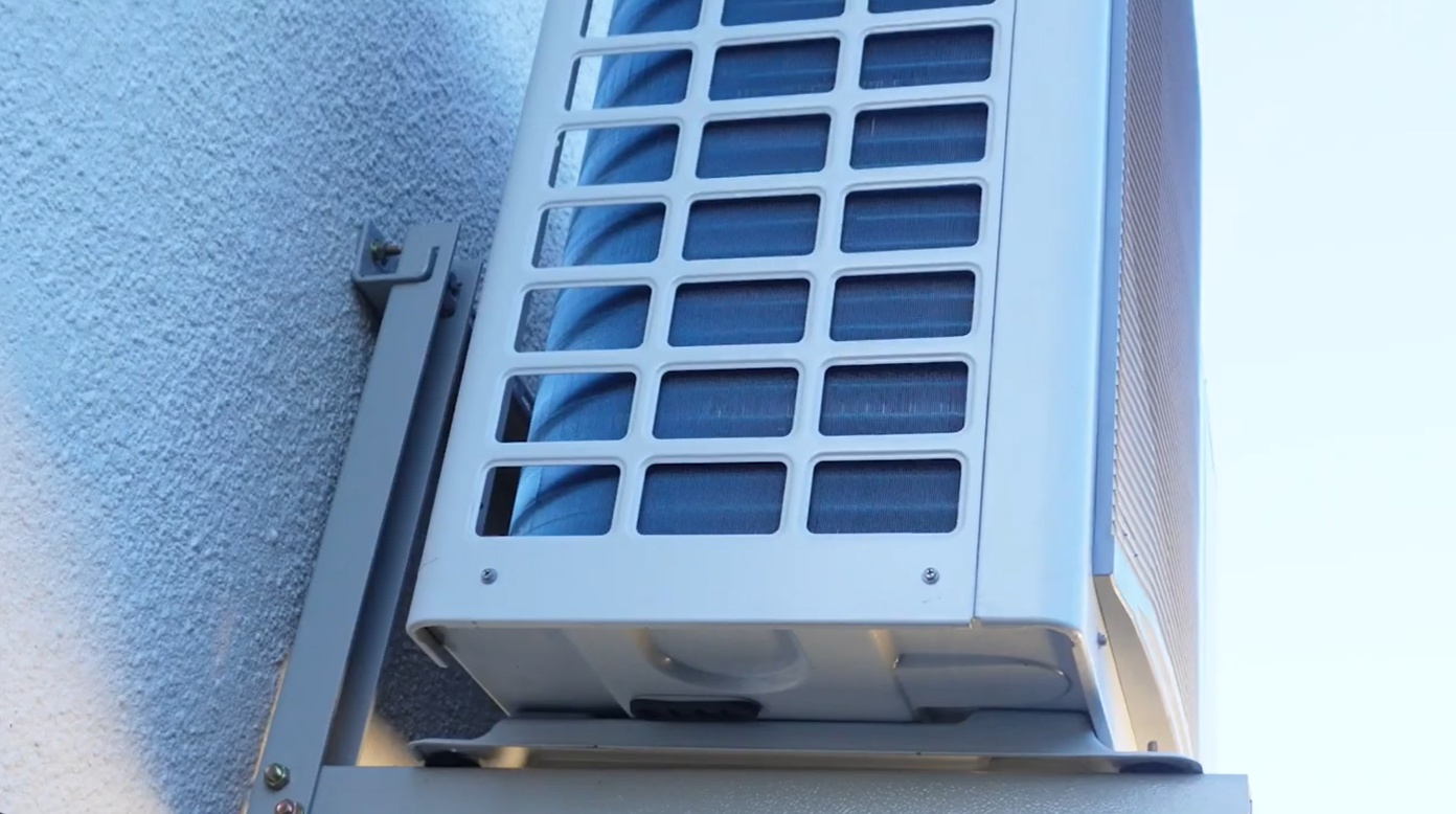 the side of a white air source heat pump that shows grill