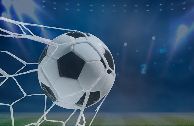 Football hitting the net in a stadium under bright lights